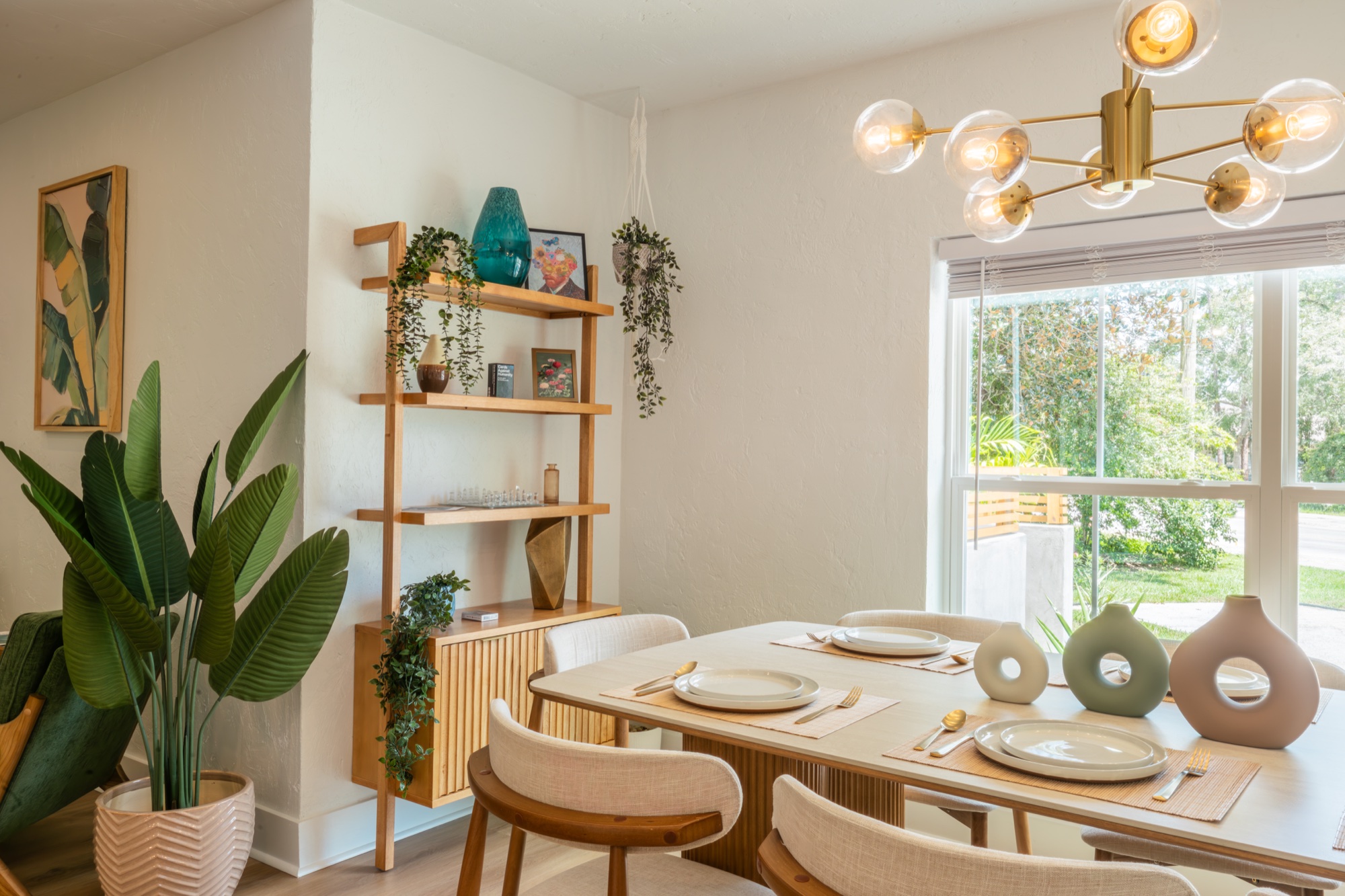 Dining nook with shelving, plants, and brass chandelier